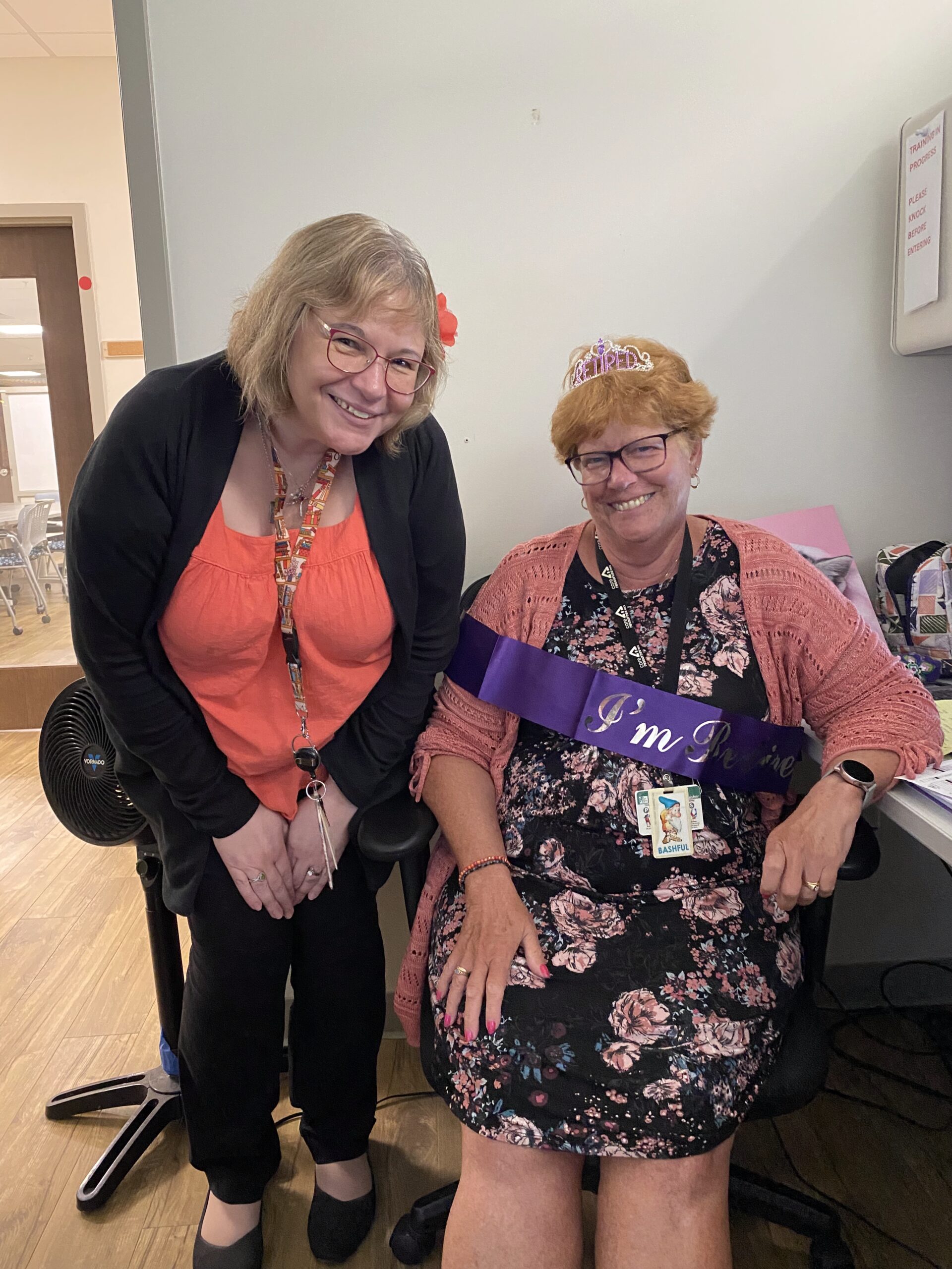 Cindy smiling while seated for a photo with a coworker