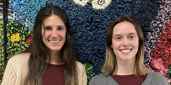 Interns Elise and Kate Social Work Interns Elise and Kate smiling in front of a colorful art piece at the day center